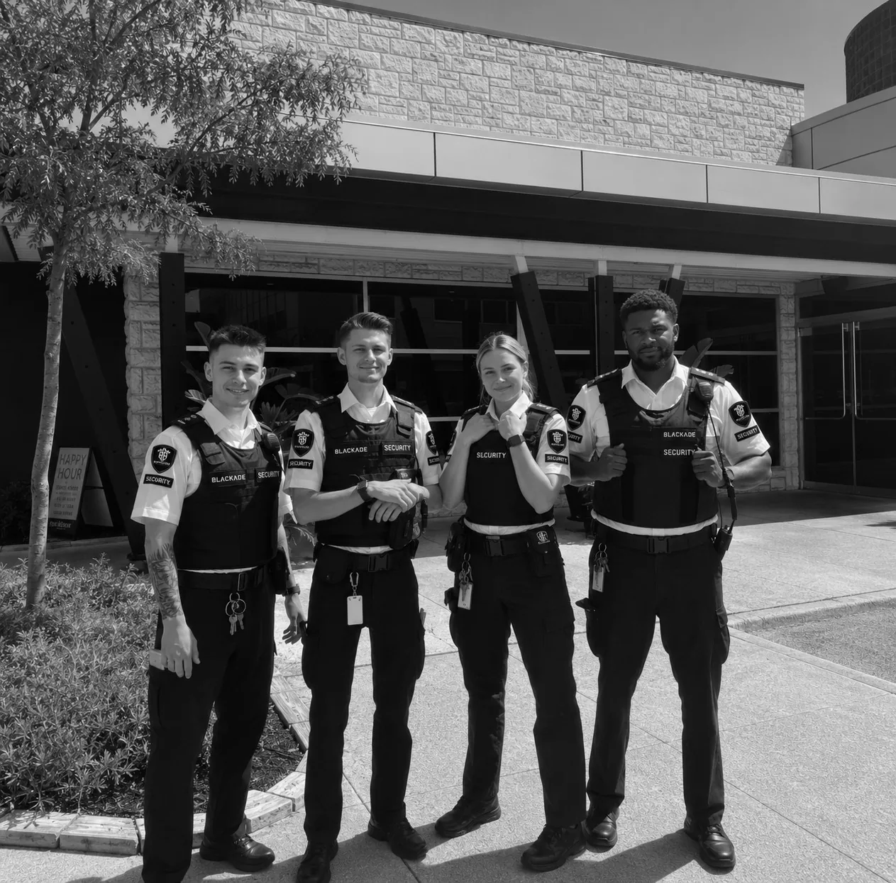 Four Blackade Security guards standing in uniform outside a commercial building