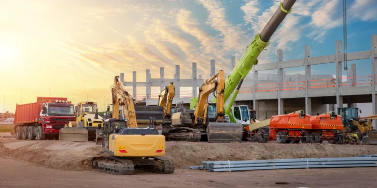 Excavators and heavy equipment on an active construction site at sunset