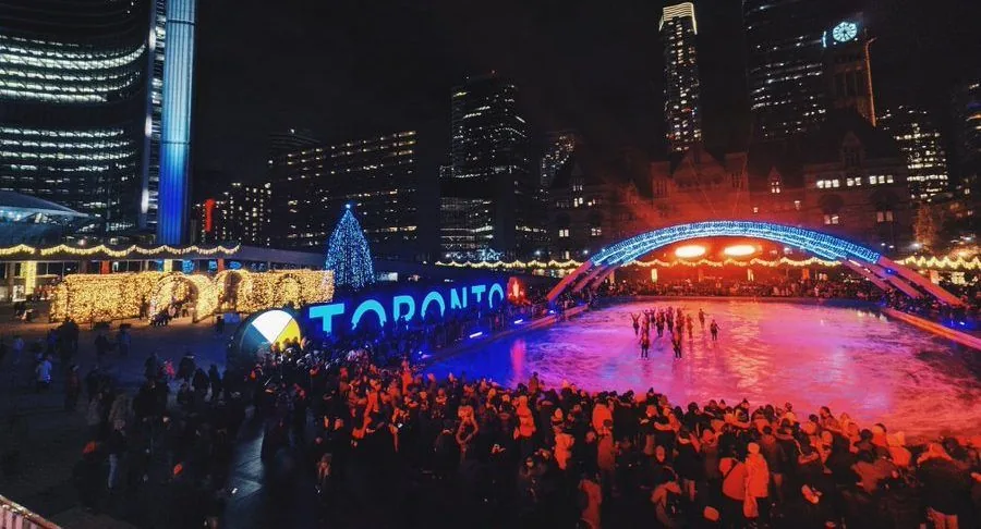 Toronto city hall ice rink at night with crowds and holiday lights